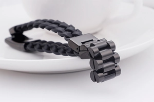 Detail of the mechanical metal clasp and black woven leather texture on the men's bracelet