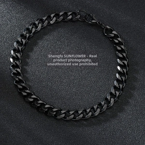 Detail view of black stainless steel Cuban link bracelet with lobster clasp on leather texture