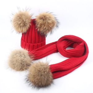 Detailed close-up of red knit hat and scarf set with fluffy brown faux fur pompoms