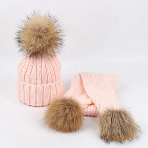 Detailed knit texture of pink winter hat and scarf set with soft faux fur pom-poms