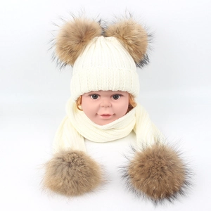 Detail view of winter baby knit hat and scarf set with two fluffy faux fur pom-poms