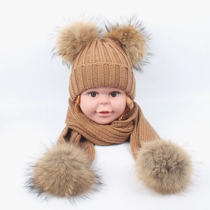 Detail of camel knit baby winter hat and scarf set featuring four fluffy faux fur pom-poms