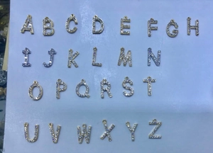 Detailed flat lay of 26 micro-pave zircon initial pendants in gold finish with hangers