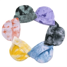 Detailed flat lay of six colorful tie-dye knitted beanies arranged in a circular display