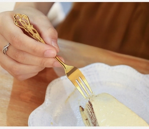 Close-up of golden vintage European embossed dessert fork with intricate handle carving
