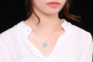 Close-up of sparkling rhinestone paw pendant necklace on female model with white shirt