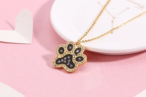 Detail of a gold paw print pendant with clear rhinestones and black inlay on a chain