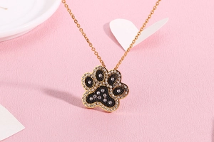 Detailed close-up of golden cat paw pendant with black filling and sparkling rhinestones