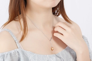 Silver thin chain necklace with a round golden shell pendant on a female model