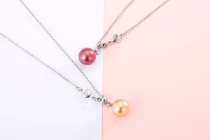 Detail view of pearl pendant necklaces with heart charms in red and gold finishes