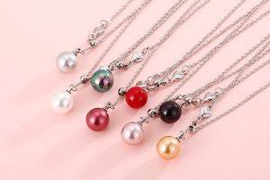 Detail showing various colored pearl necklaces with heart pendants on a pink surface