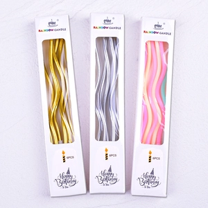 Detailed view of three packs of gold, silver, and pink curved spiral birthday candles