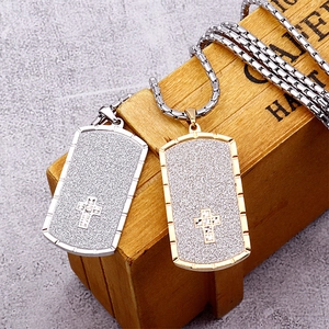 Detail view of silver and gold cross pendant necklaces with matte finish on wooden stand