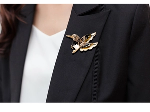 Detailed hummingbird brooch featuring black enamel and crystals on a black suit lapel