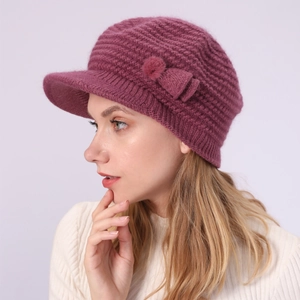 Detail einer lila Strickmütze mit Schirm, Bommel und Schleife für warme Wintertage