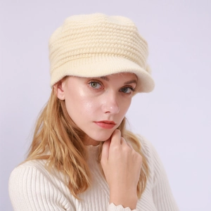 Nahaufnahme der beigen Strickstruktur und des Schirms einer warmen Wintermütze