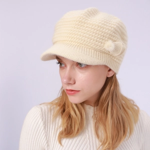 Detailansicht der beigefarbenen Strickmütze mit Schirm, Strickmuster und weichem Bommel