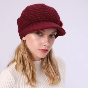 Detail der Strickstruktur der weinroten Schirmmütze mit Bommel und Schirm für Damen