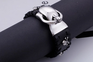 Close-up of black leather punk bracelet featuring silver skull charms and metal buckle