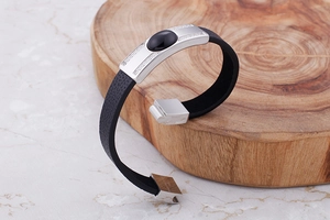 Detail of men's geometric stainless steel bracelet with black stone on a wooden plate