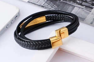 Detail of multi-layer black woven leather bracelet with polished gold magnetic clasp