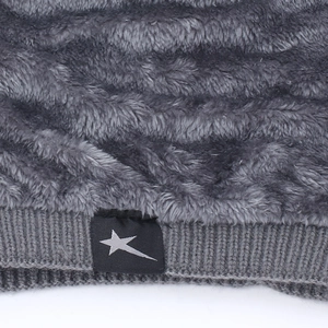 Detail of windproof dark gray knit hat featuring soft fleece lining and star woven label