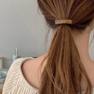 Detail of tortoiseshell acetate geometric hair tie worn on a ponytail with black elastic