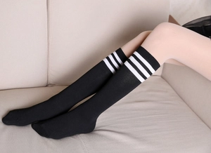Detail of black over-knee socks with triple white stripes on elastic cotton fabric