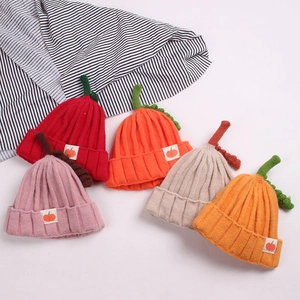 Close-up of knit pumpkin hats for kids in red, pink, orange, beige, and yellow colors