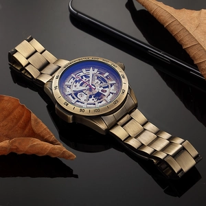 Macro shot of bronze skeleton automatic mechanical watch with visible gears and tachymeter