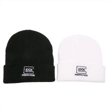 Close-up of black and white knit beanies with Glock Perfection embroidered logos