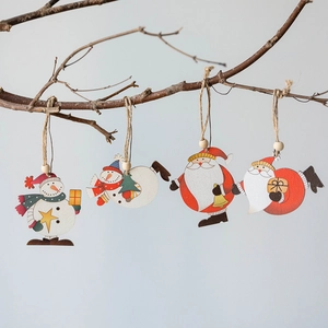 Set of four wooden Christmas ornaments with Santa and snowman patterns hanging on a branch