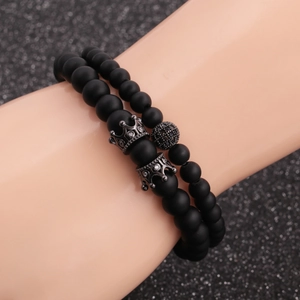 Close-up of matte black bead bracelets featuring crown charms and micro-pave disco balls