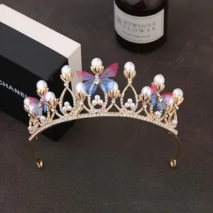 Detailed close-up of golden alloy crown with rhinestones, pearls and gradient butterflies
