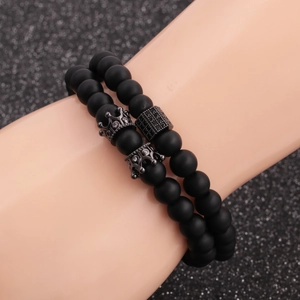 Macro view of matte black beaded bracelets featuring a crown and micro-set zircon bead