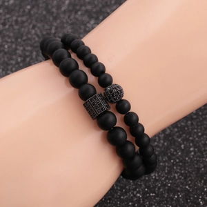 Detail of matte black stone bracelet set with micro-pave crown and cross charms
