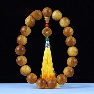 Macro detail of aged Thuja sutchuenensis wood beads with red oil texture and yellow tassel