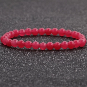 Vista detallada de una pulsera de cuentas de ágata roja de 6mm sobre un fondo negro texturizado