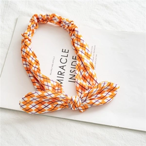 Détail d'un bandeau oreilles de lapin en velours à carreaux orange et violet avec un nœud