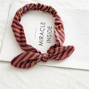Détail d'un bandeau en velours rayé violet et orange avec nœud oreilles de lapin sur carte