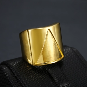 Close-up of golden stainless steel ring with geometric triangle engraving on black base