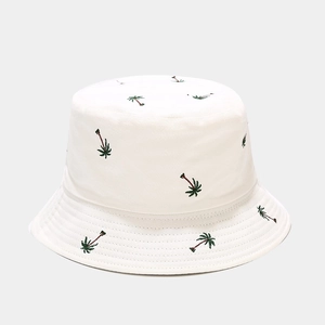 Detailed view of green palm tree embroidery on a high-quality white cotton bucket hat