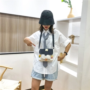 Détail d'un sac bandoulière en toile avec écussons tournesol et ours sur une tenue