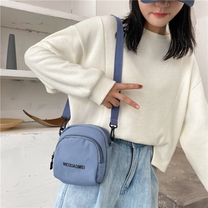 Blue nylon crossbody bag with black MEIXIAOMEI lettering shown on a female model