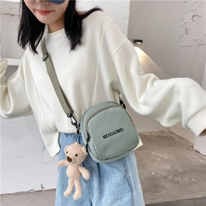 Close-up of bean green crossbody bag with cute brown plush bear charm detail