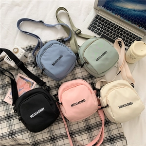 Flat lay of canvas crossbody bags in blue, green, black, pink, and off-white colors