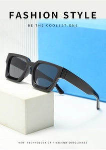 Modern thick black square frame sunglasses displayed on minimalist blue blocks