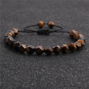 Detailed macro view of 8mm faceted tiger eye stone beads on adjustable braided cord bracelet