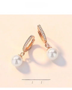 Close-up of rose gold silver pearl earrings featuring sparkling zircon accents and white beads