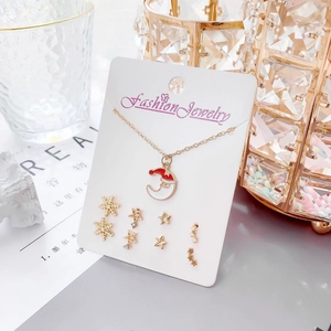 Gros plan du collier lune doré et boucles d'oreilles flocon sur carte blanche